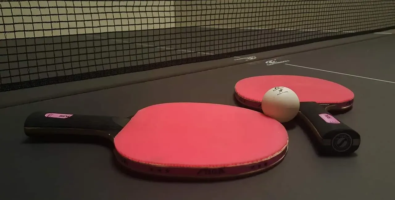 Tischtennisschläger und Ball an einer Tischtennisplatte