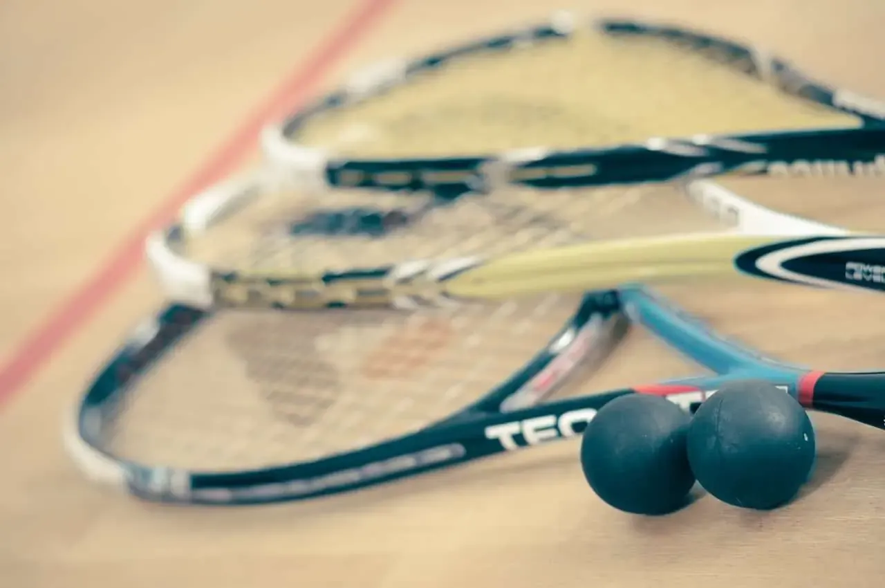 Squashschläger und Bälle auf dem Hallenboden